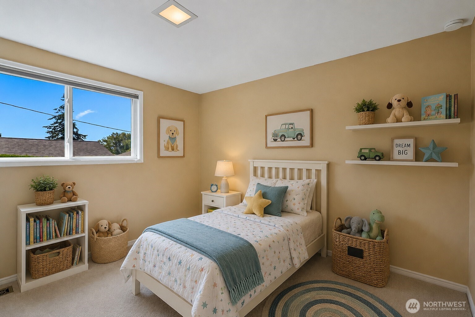 Staged children's bedroom with a white bed, blue throw, toy-filled shelves, and a large sunny window.