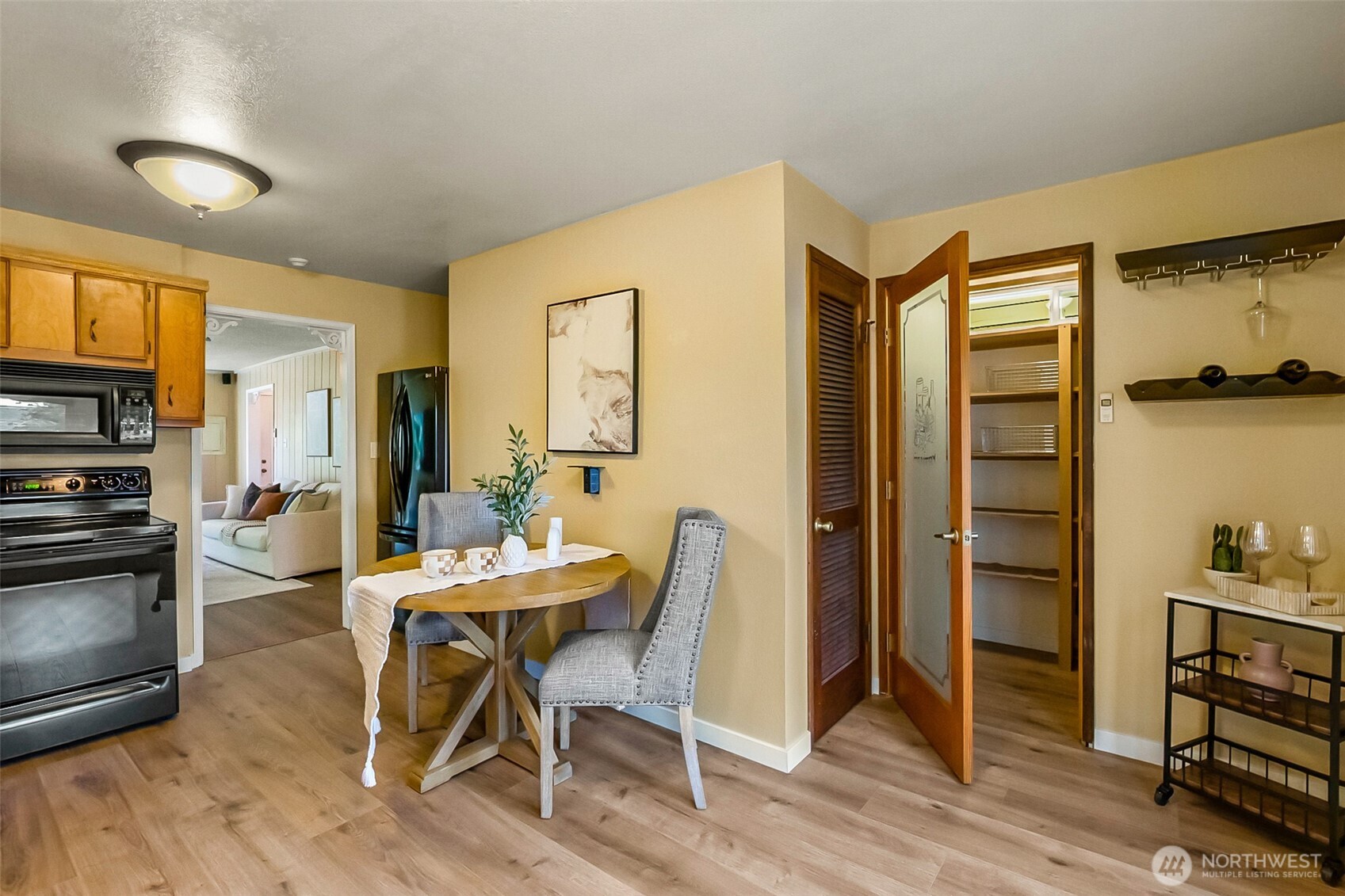 Dining area with a round wood table beside the kitchen and an open pantry.