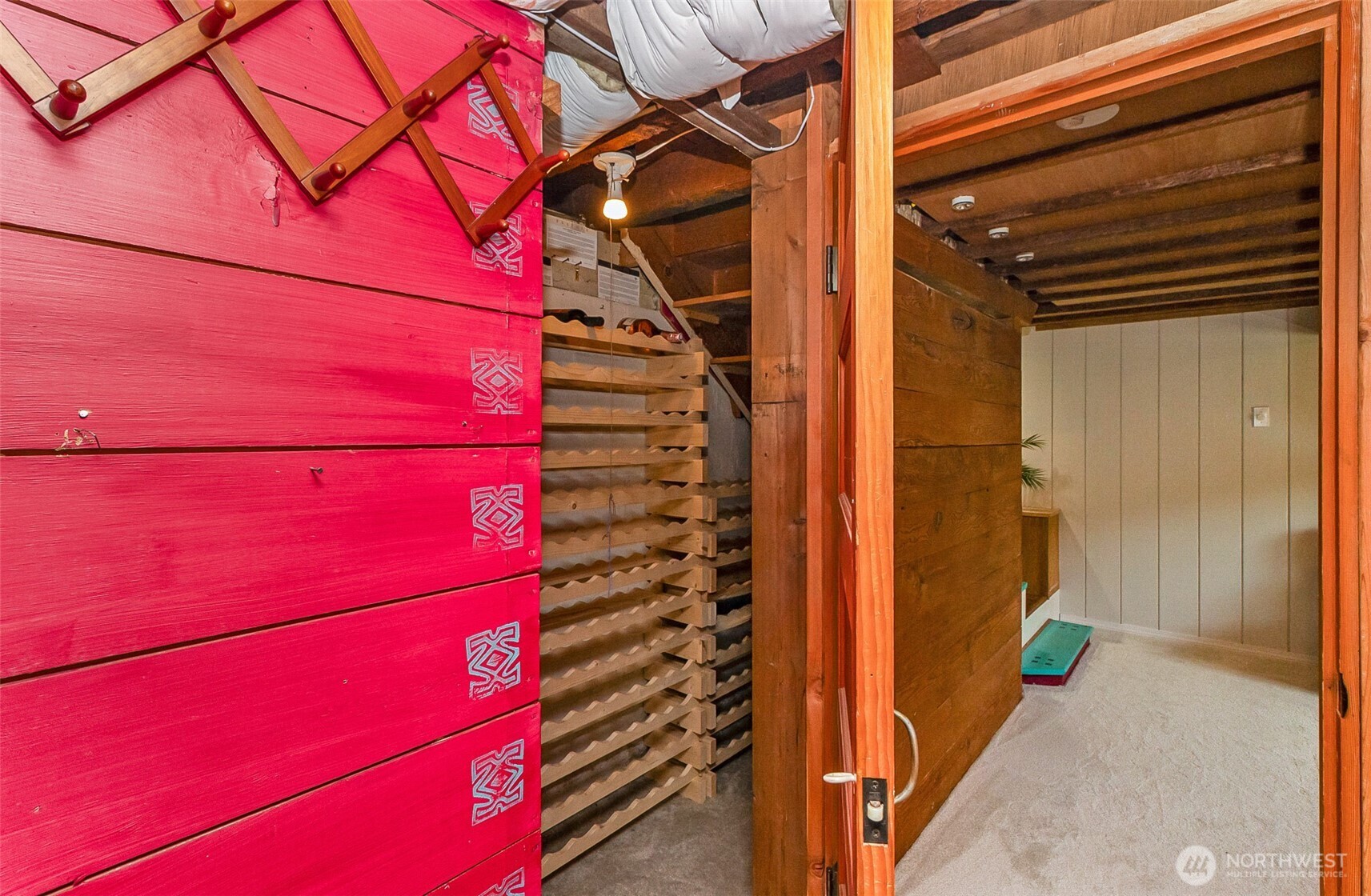 Wine cellar with wooden bottle racks and bright red storage cabinets beside an open doorway.