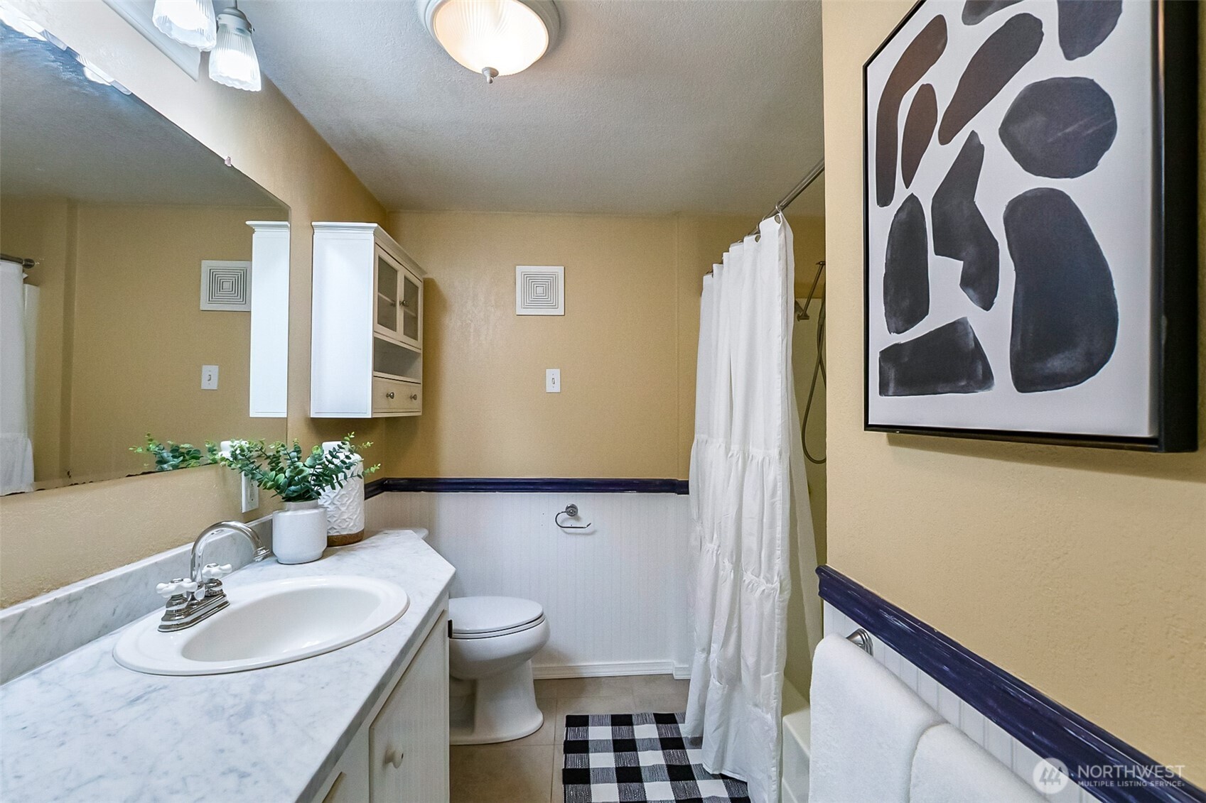Bathroom with a marble-look vanity, white shower curtain, and black-and-white checkered rug.