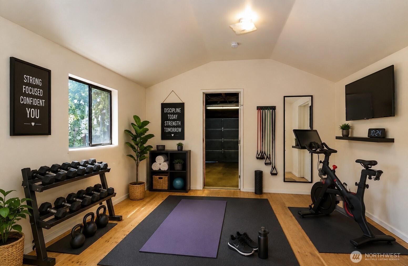 Home gym with dumbbell rack, stationary bike, resistance bands, and a purple yoga mat.