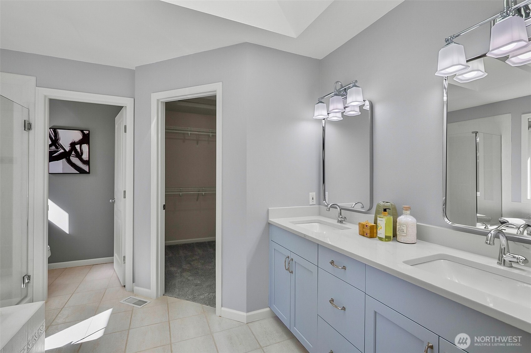 Primary bathroom with a pale-blue double vanity, two sinks, and an open walk-in closet.