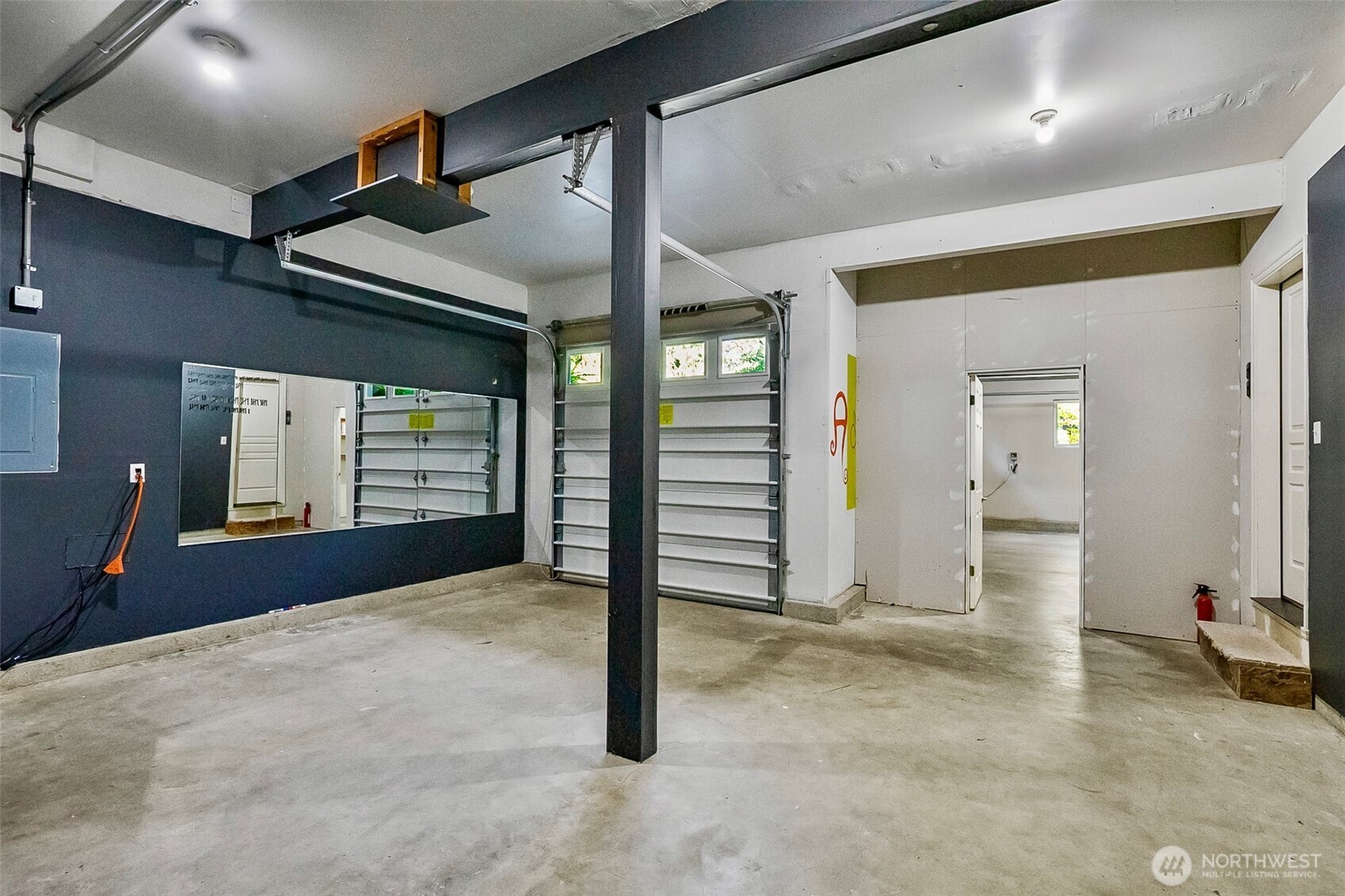 Spacious garage with a concrete floor, overhead storage, and a central support post.