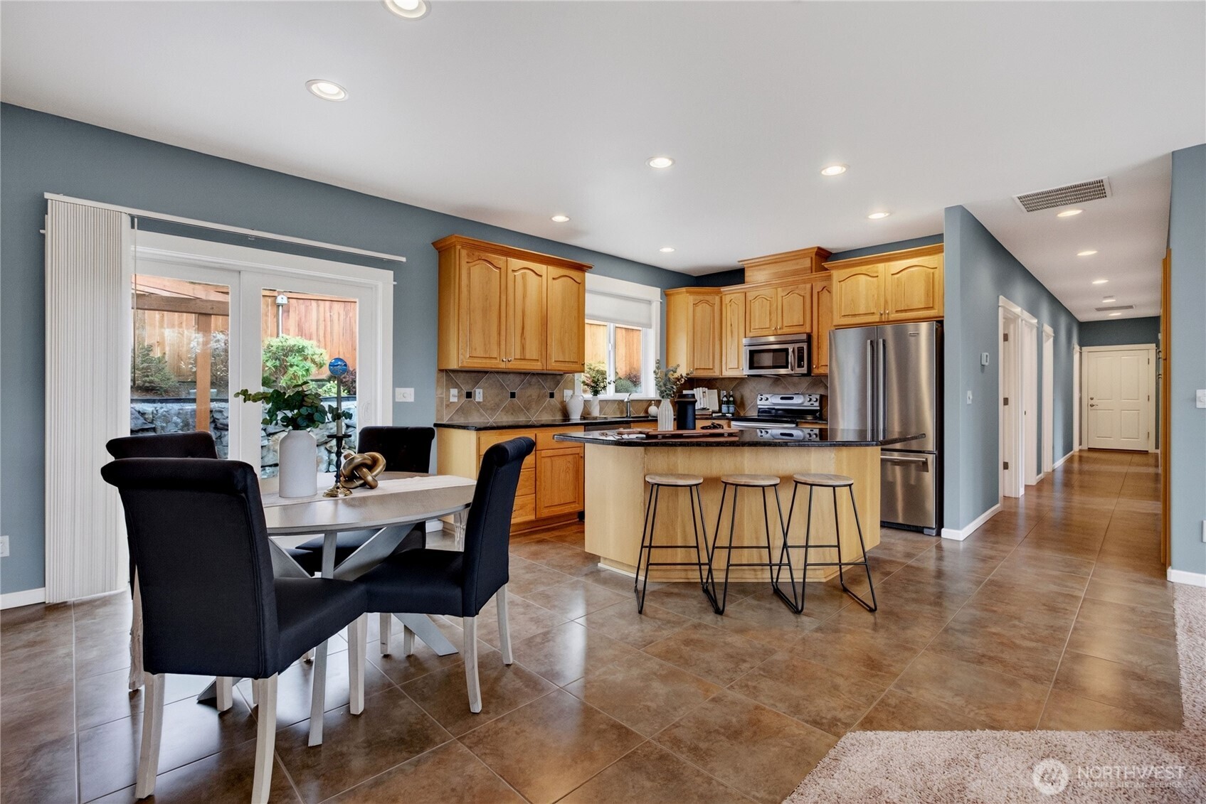 Kitchen with wood cabinets, stainless steel appliances, a large island, and dining area by sliding glass doors.