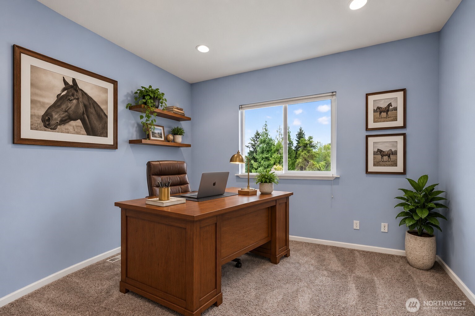 Furnished home office with a wooden desk, horse artwork, and a window overlooking trees.