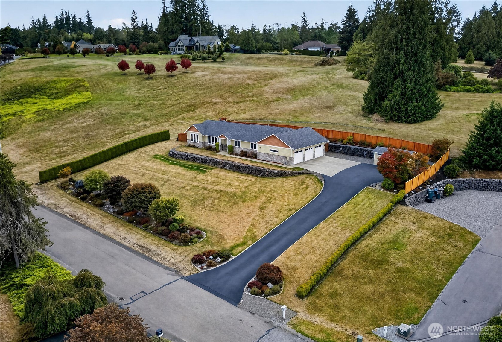 Single-story home with a three-car garage, long driveway, and expansive open lawn.