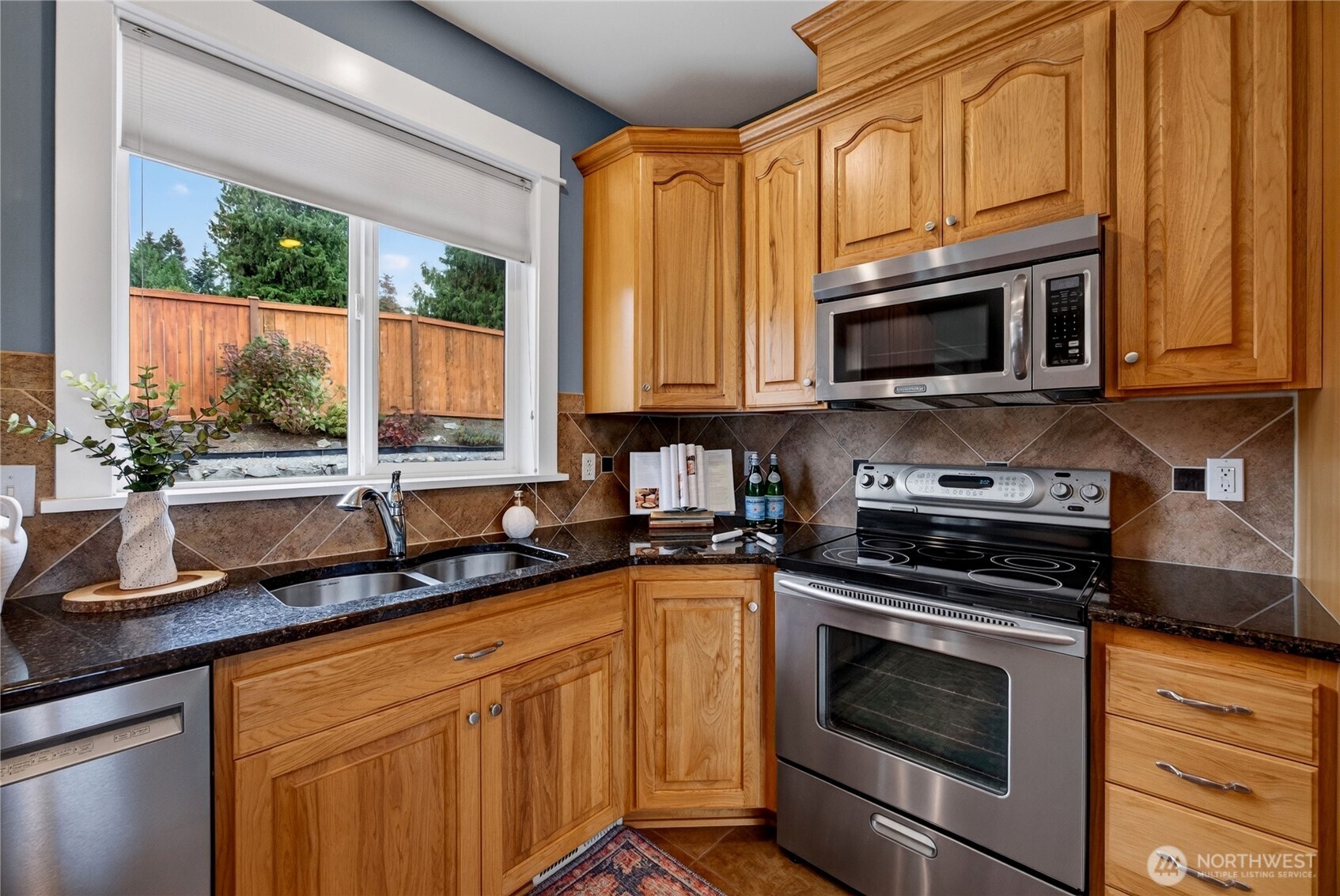 Kitchen with honey-colored wood cabinets, dark countertops, and stainless steel appliances.