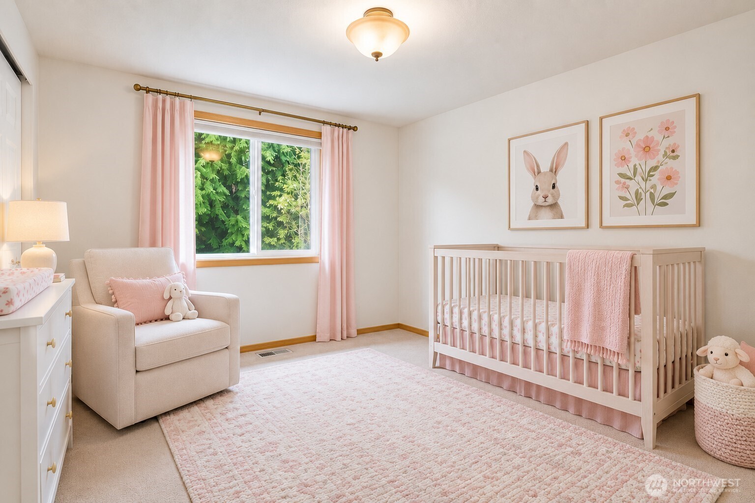 Staged nursery with a light wood crib, pink accents, and a window overlooking greenery.