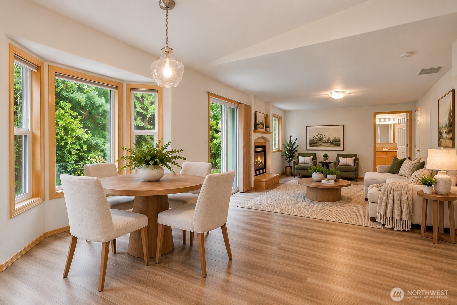 Open-plan dining and living room with large garden-facing windows and a fireplace.
