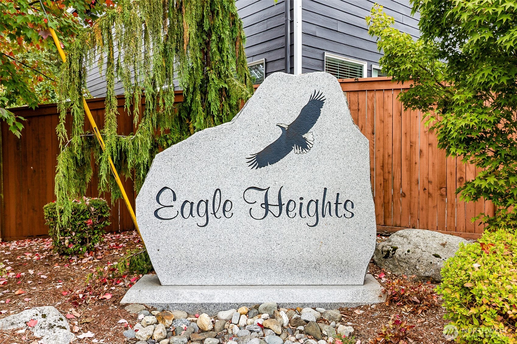 Eagle Heights neighborhood sign with an eagle silhouette, surrounded by landscaping and a wooden fence.