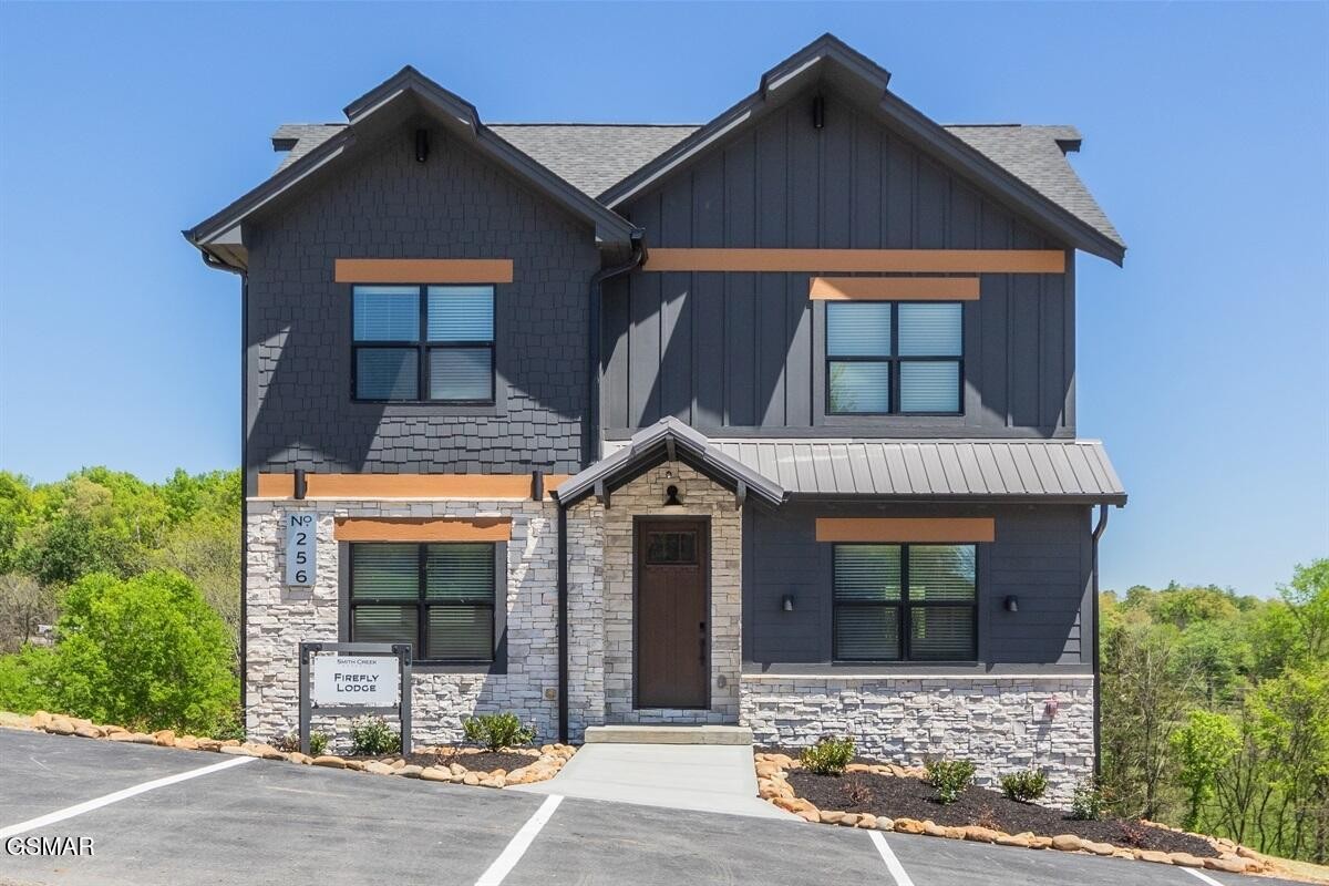 Two-story lodge with dark siding, stone veneer, orange trim, and a Smith Creek Firefly Lodge sign.