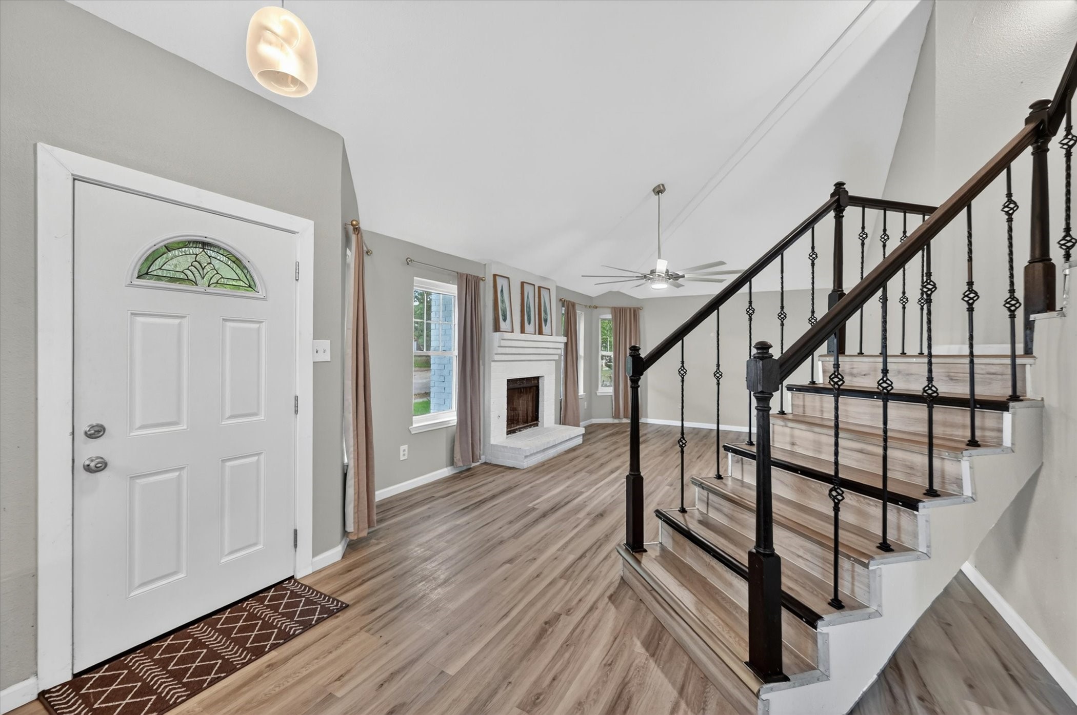 Entry foyer with a stained-glass front door, white fireplace, and staircase with dark metal balusters.