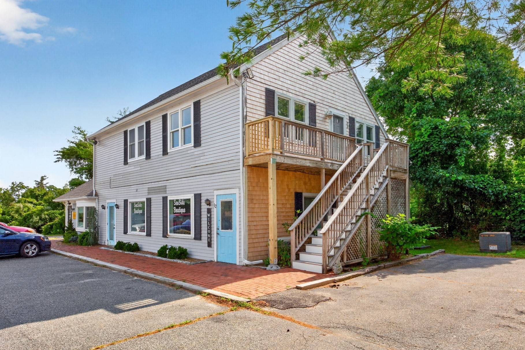 Two-story shingled building with a boutique storefront and wooden stairs leading to a second-floor balcony.