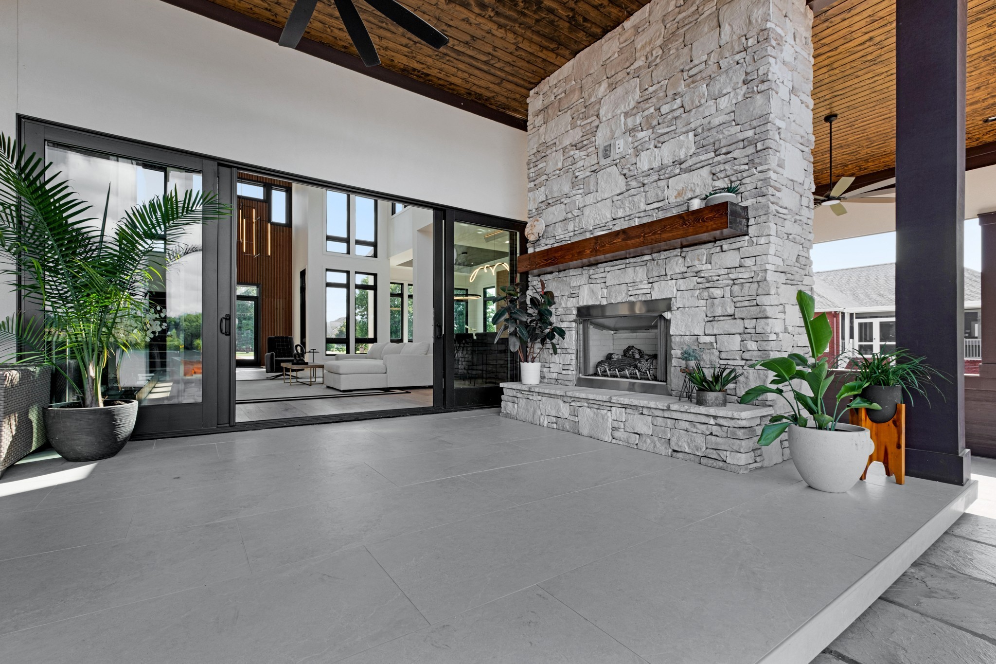 Covered patio with a floor-to-ceiling stone fireplace and sliding glass doors to the living room.