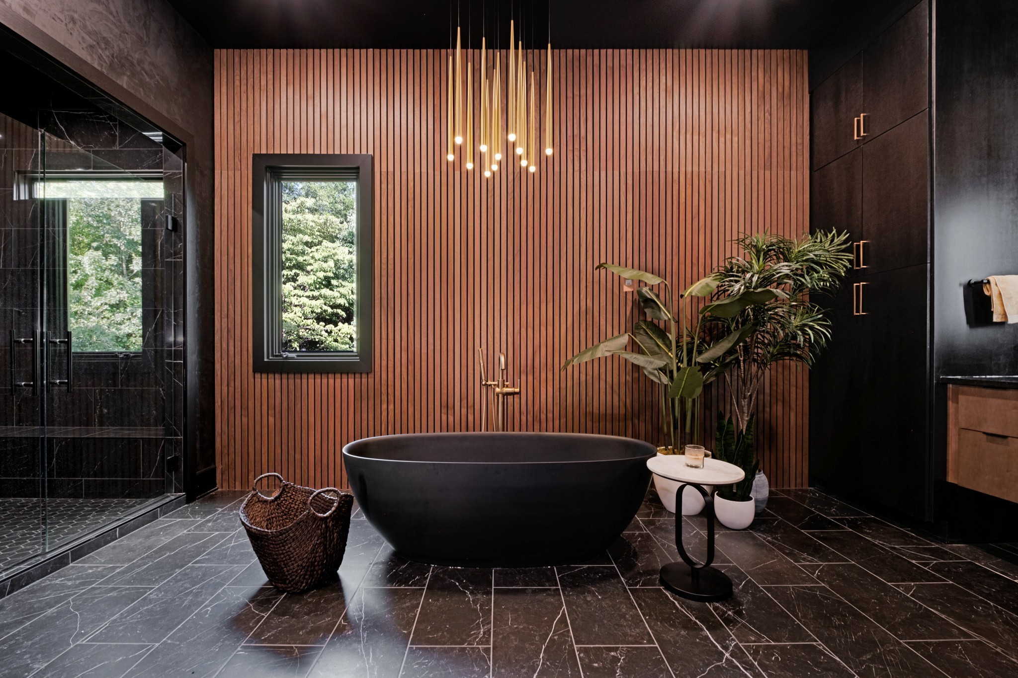 Modern bathroom with a black soaking tub, glass shower, and wood-slat accent wall.
