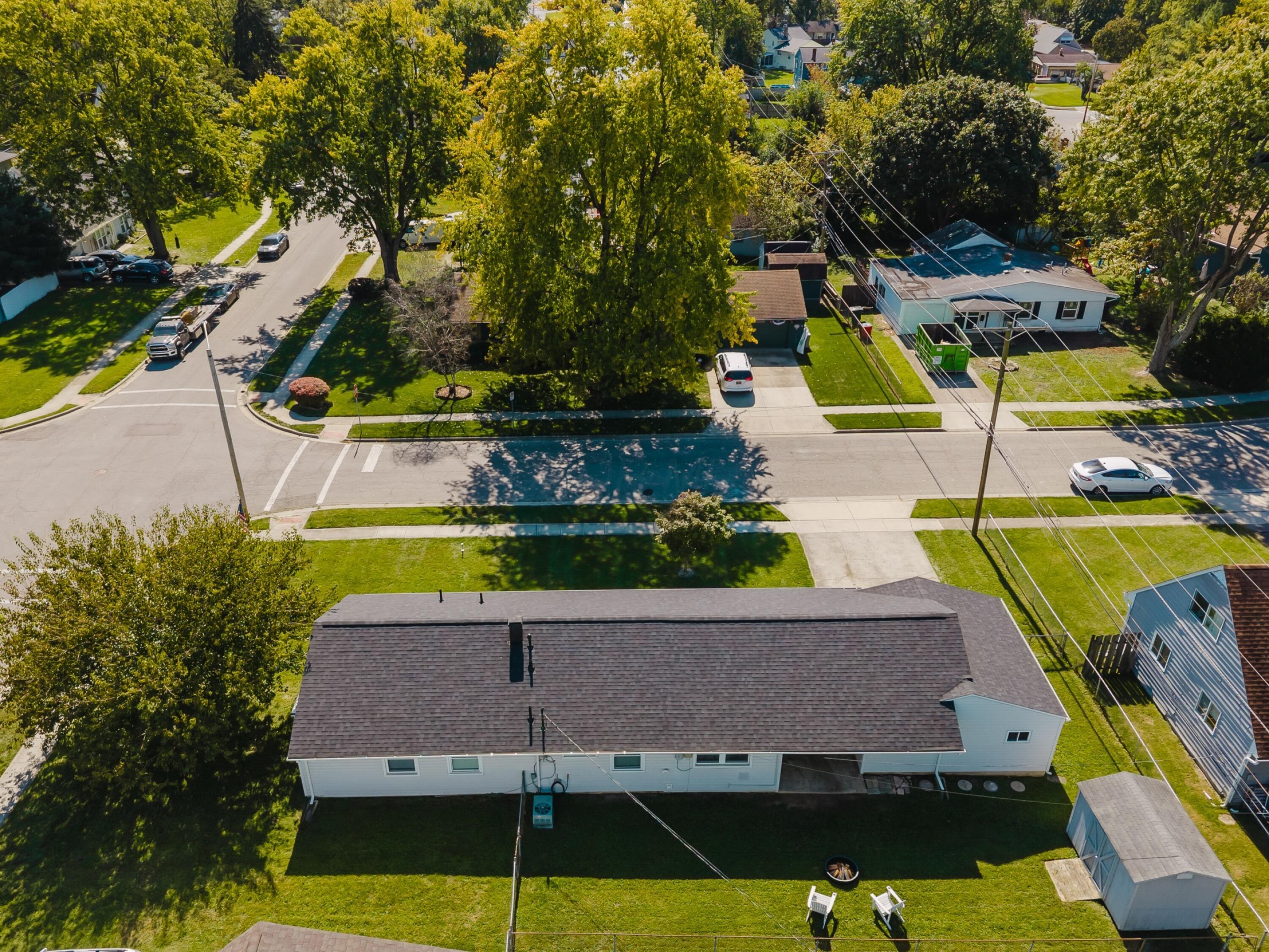 Aerial view of a white single-story home with a fenced backyard and detached shed.