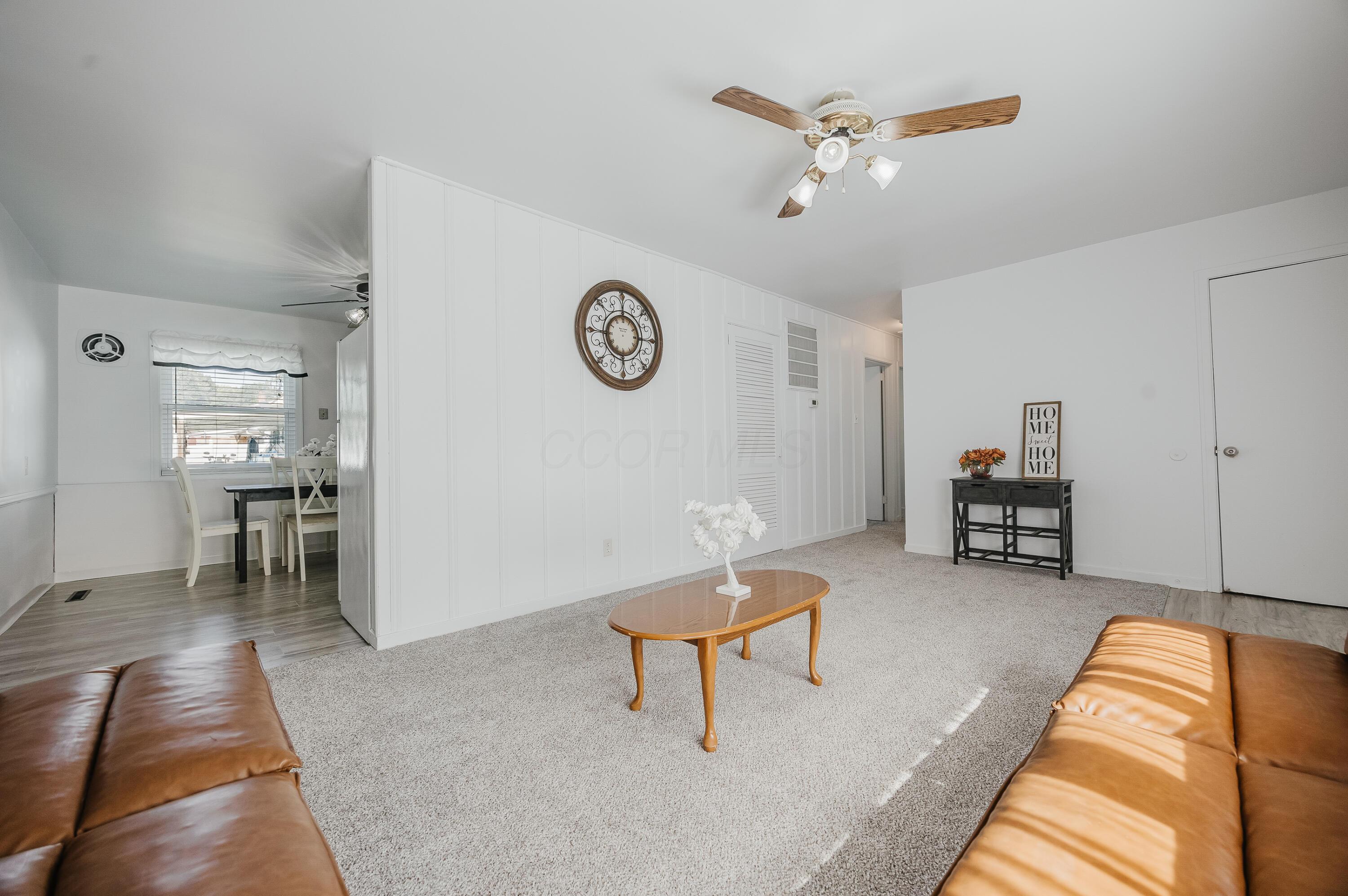 Living room with brown leather sofas, a wooden coffee table, and an adjoining dining area.