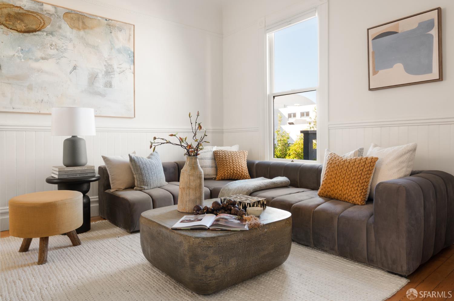 Staged living room with a gray sectional, textured pillows, and a rounded coffee table.