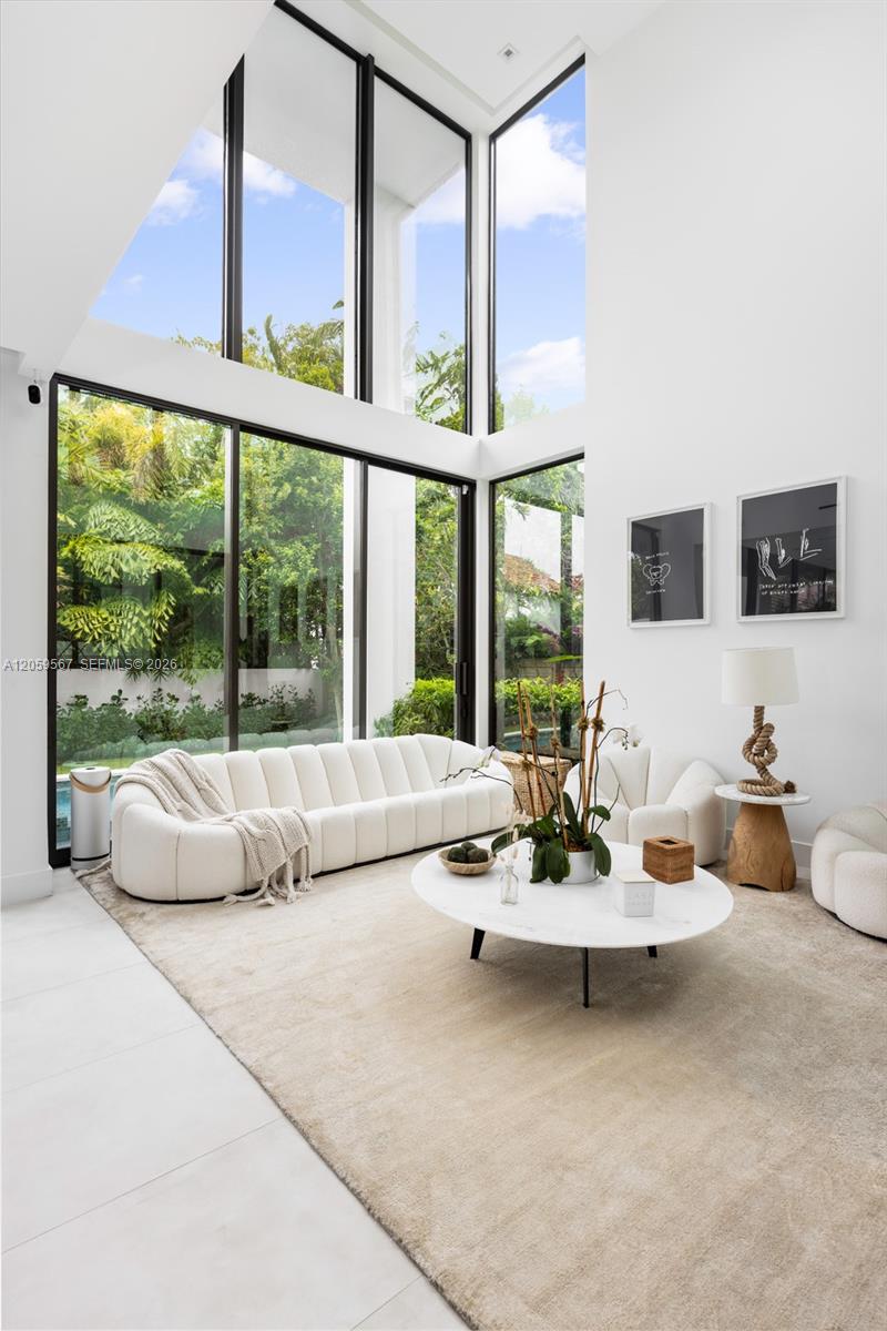 Living room with a white sectional and soaring garden-facing windows.