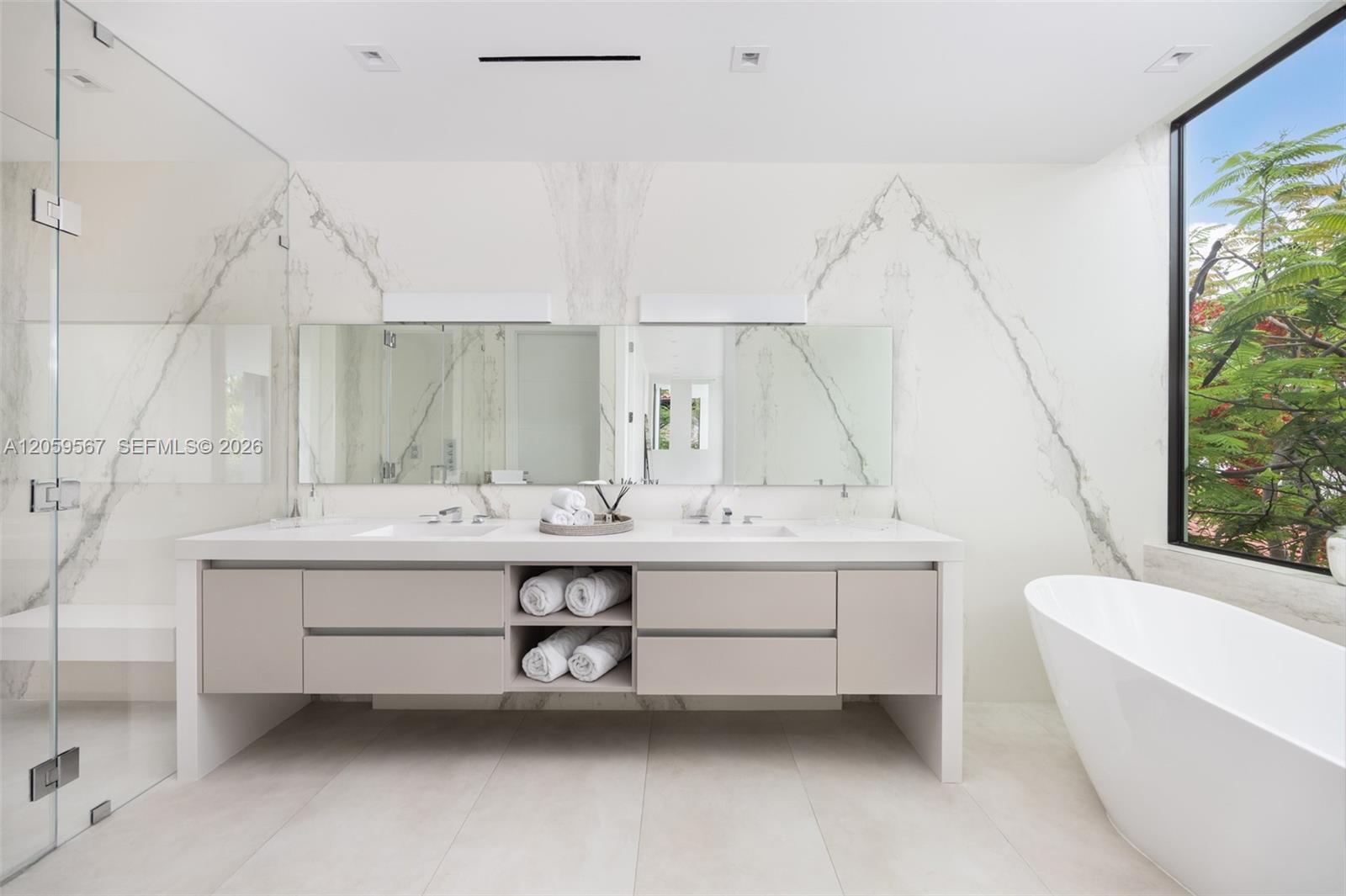 Modern bathroom with double vanity and freestanding tub beside a large window.