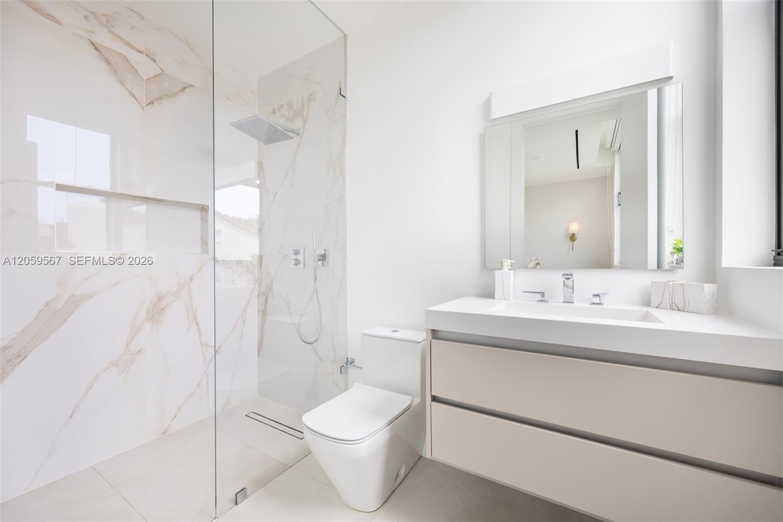 Modern bathroom with a glass shower, veined marble-look walls, and a floating vanity.