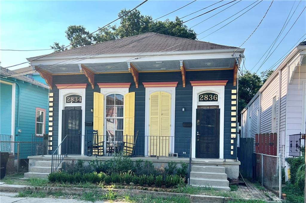 Dark blue duplex with yellow shutters, two numbered entrances, and a covered porch.