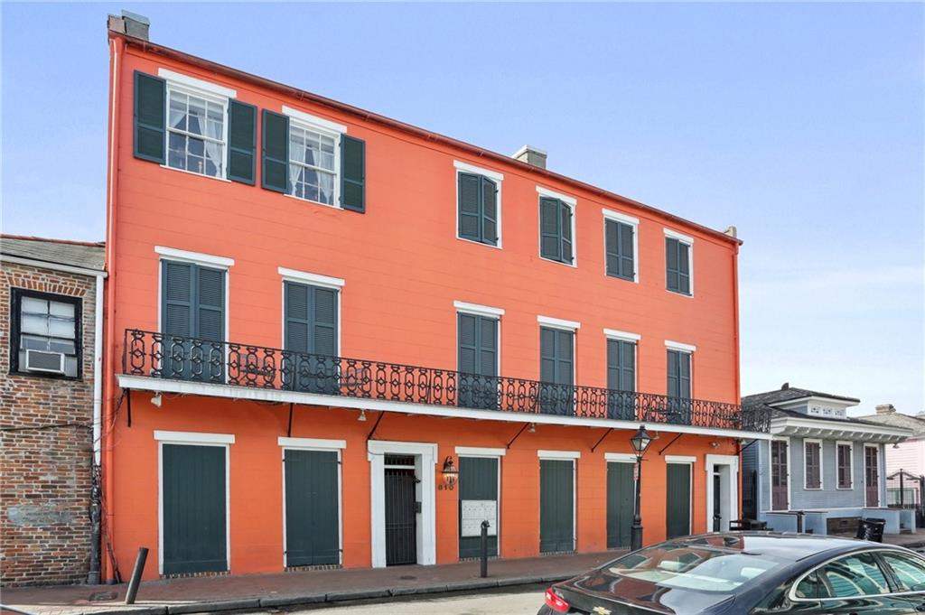 Orange multi-story building with green shutters and a wrought-iron balcony.
