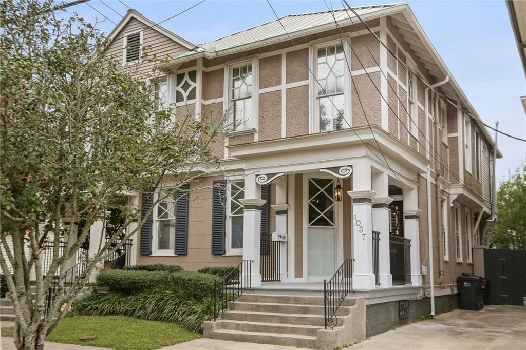 Two-story beige building with white trim, a columned porch, and front steps.