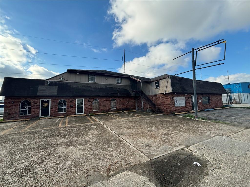 Commercial brick building with arched windows and a broad paved parking area.