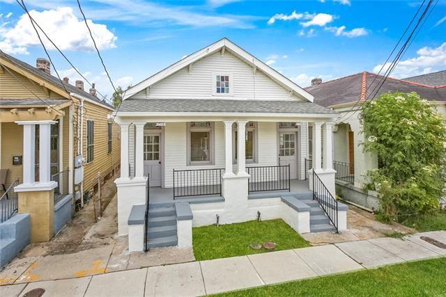 White clapboard house with a covered porch, black railings, and broad front steps.