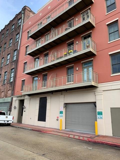 Coral-colored multistory building with stacked balconies and a ground-floor garage door.