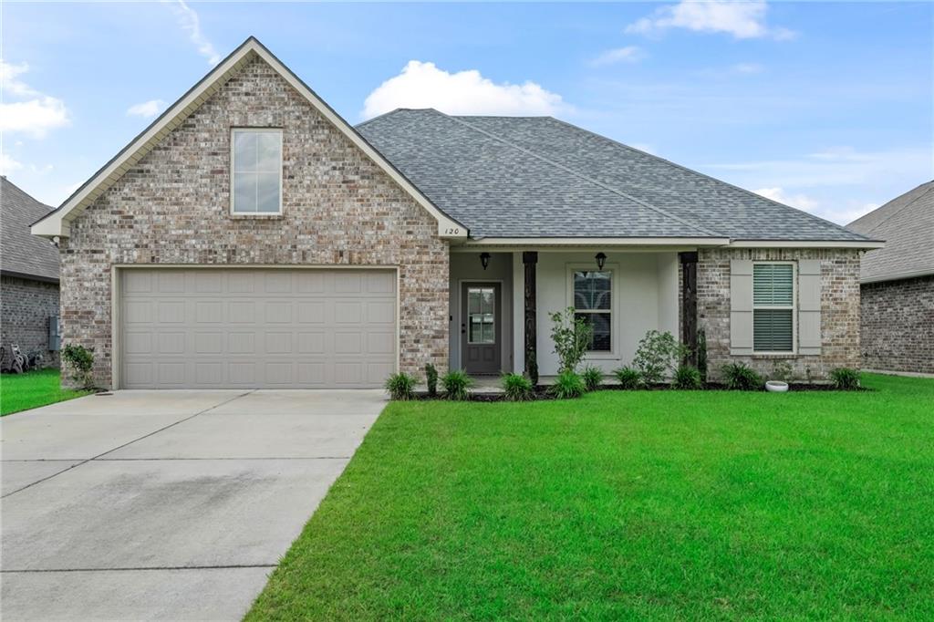 Brick house with a gabled roof, two-car garage, covered entry, and broad green lawn.