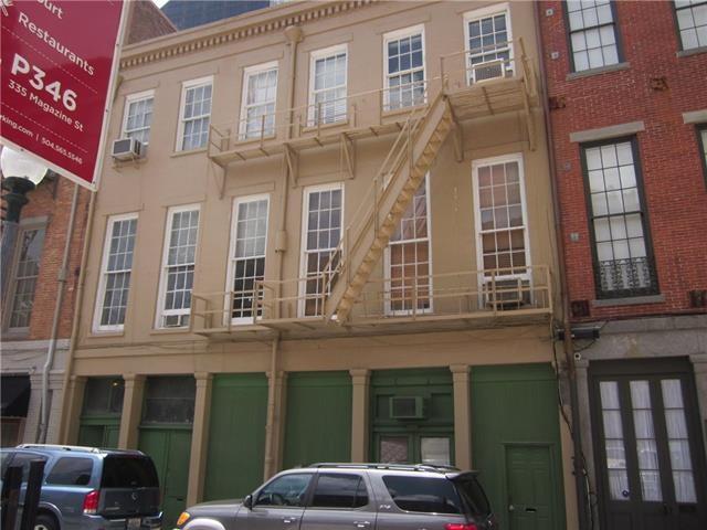 Historic commercial building with green storefronts, tall windows, and an exterior metal fire escape.