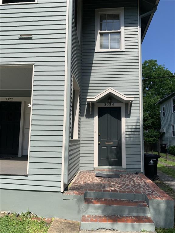 Gray-sided home with a dark front door, peaked awning, and brick entry steps.
