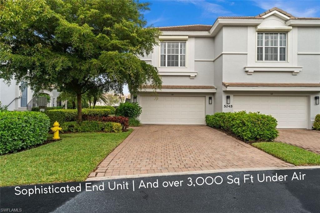 Two-story end-unit home with a brick-paver driveway, two-car garage, and landscaped front lawn.
