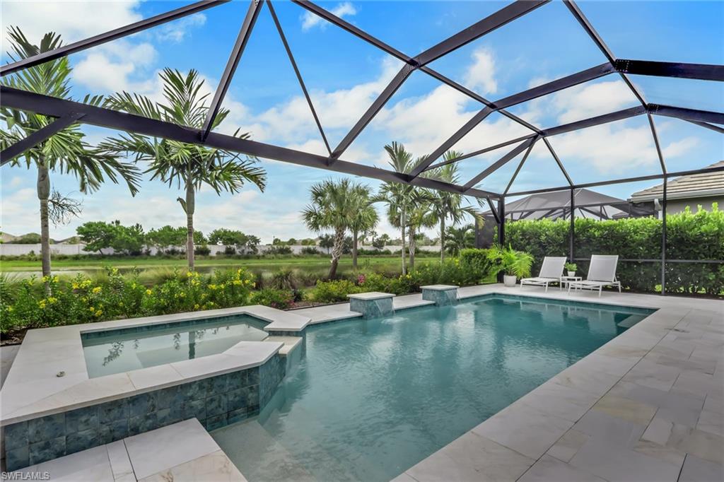 Pool beneath a screened lanai with a raised spa, tile patio, and palm trees.