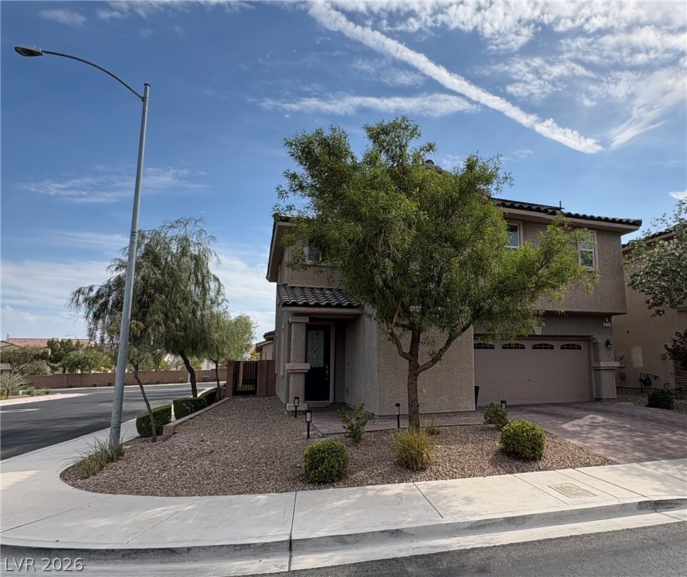 Two-story stucco home with a two-car garage and desert landscaping on a corner lot.
