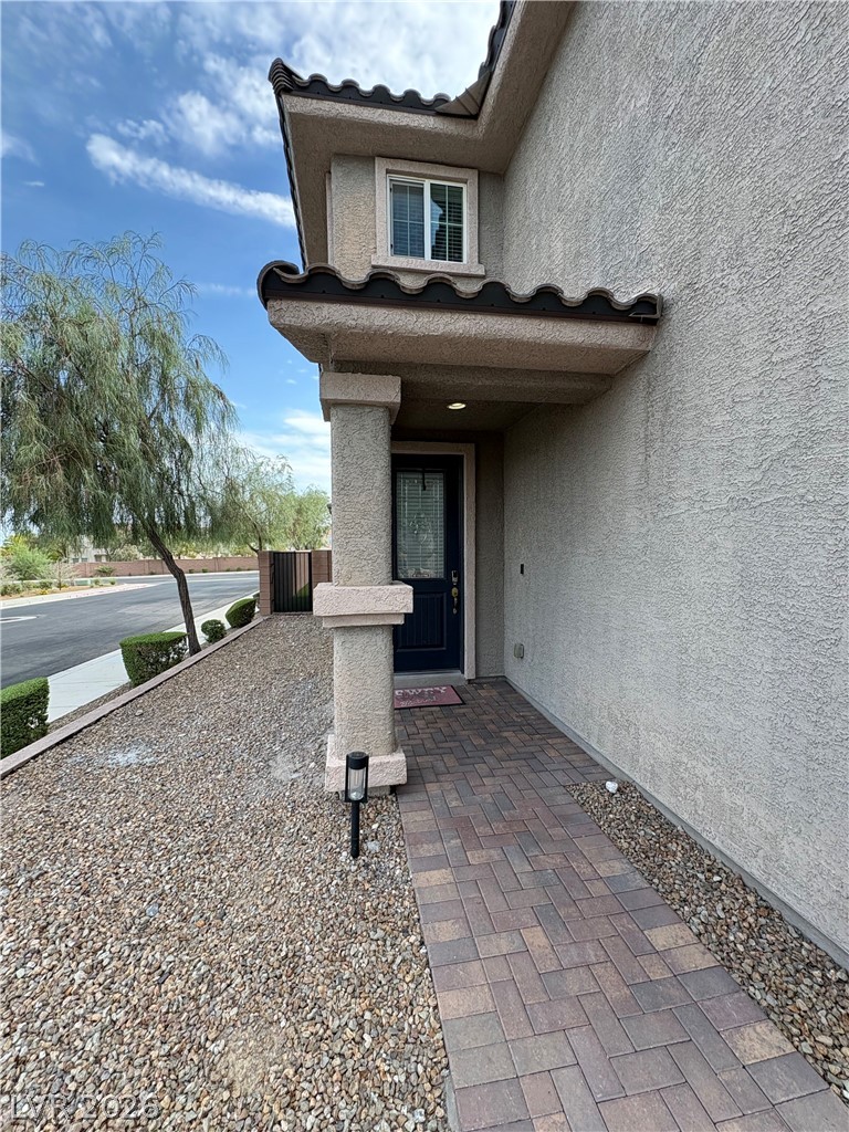 Home entry with dark tile awnings and a paver walkway through gravel landscaping.