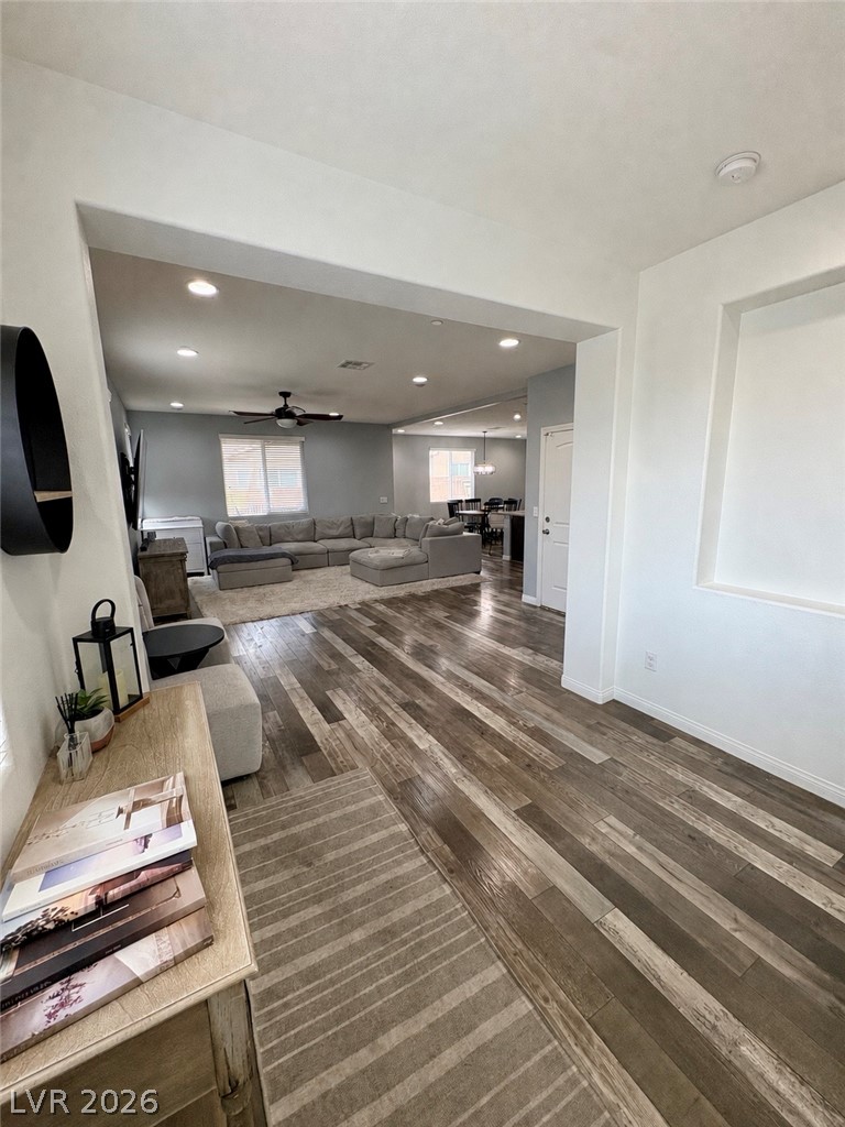 Open living room with gray sectional, wood-look flooring, and dining area beyond.