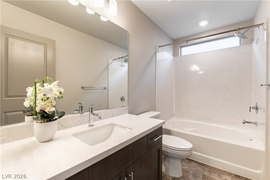 Bathroom with a marble-look vanity, dark cabinetry, bathtub, and potted white orchid.