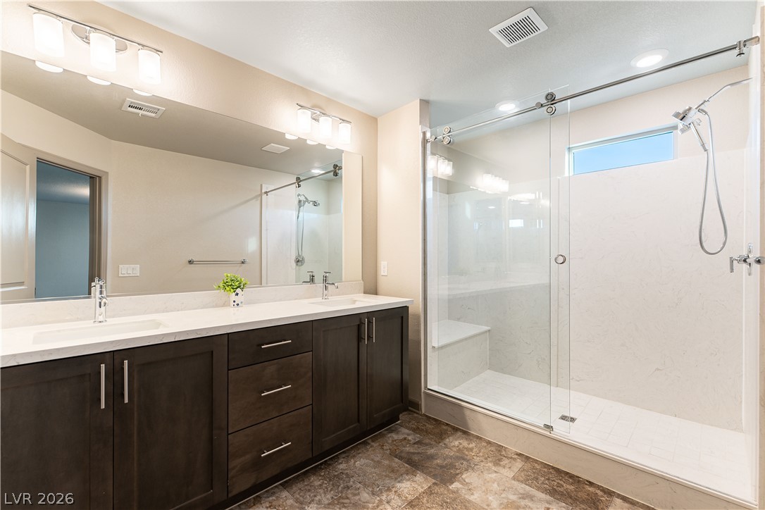 Bathroom with a double-sink vanity and spacious glass-enclosed shower.