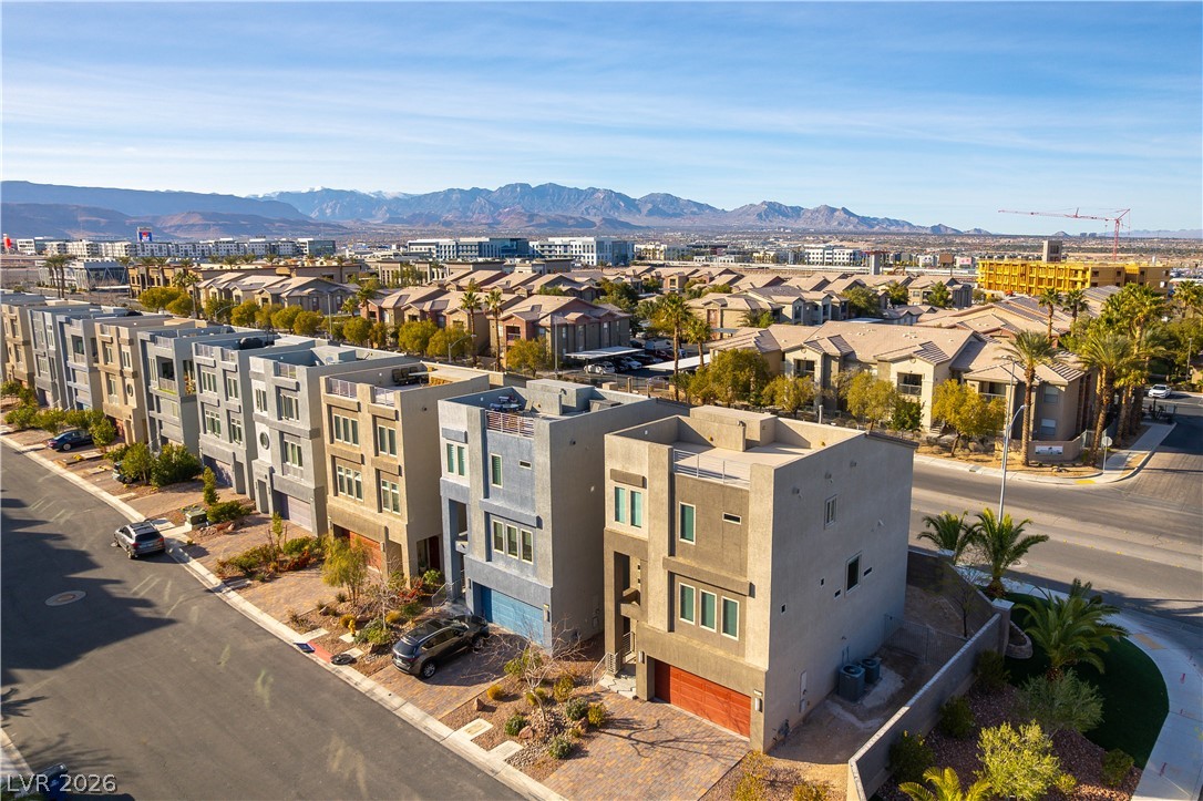 Aerial view of modern townhomes with palm trees and mountains in the distance.