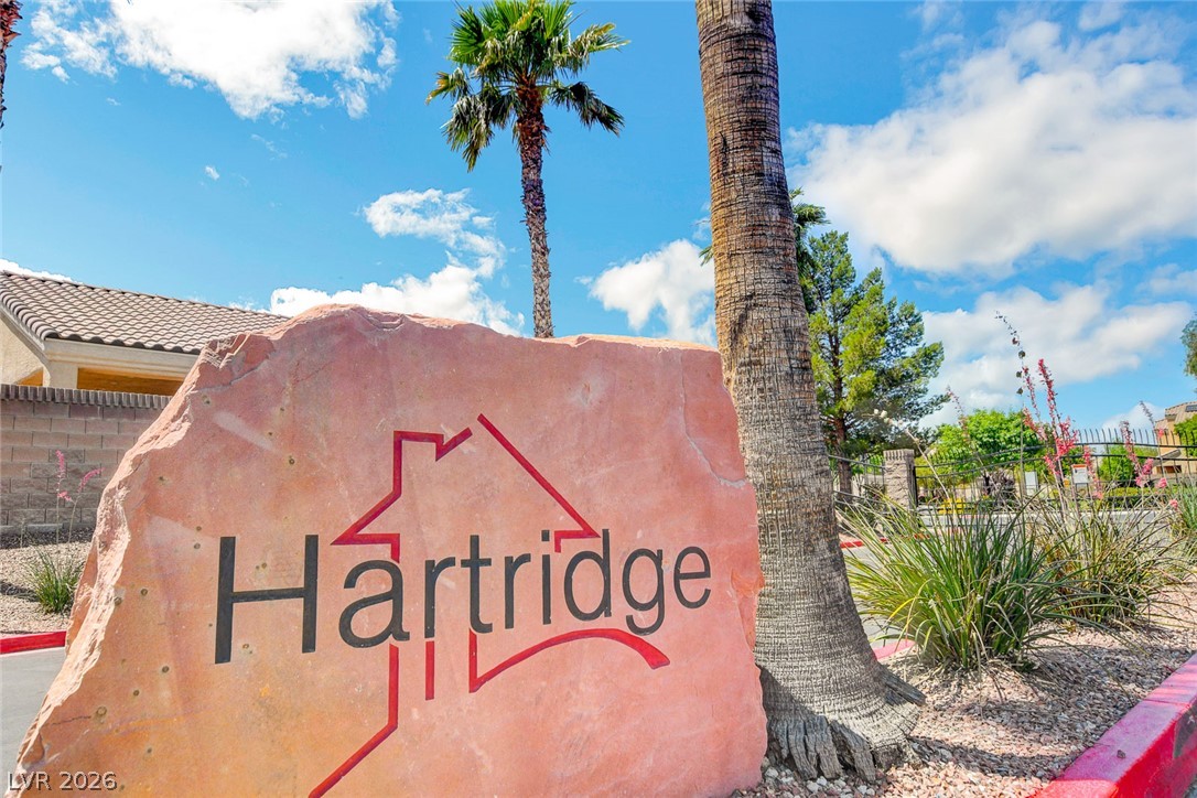 Hartridge community sign beside a palm tree and desert landscaping.