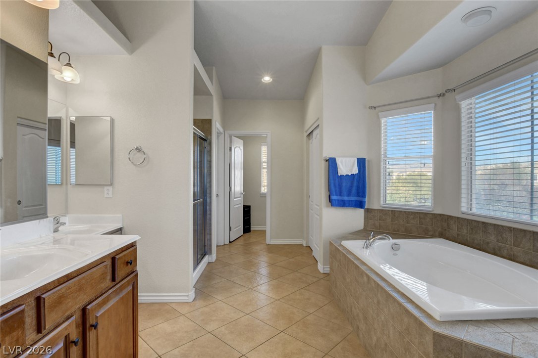 Spacious bathroom with a built-in soaking tub, double-sink vanity, and two windows with blinds.