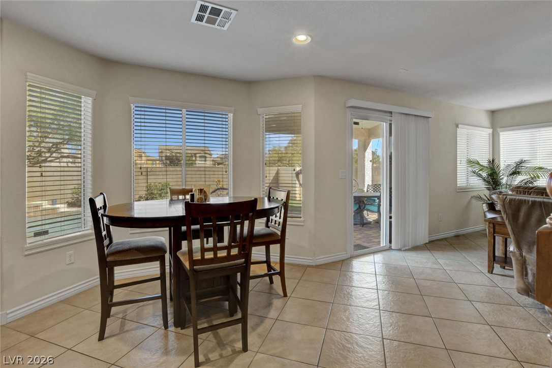 Dining area with a dark wood table beside windows and a sliding glass door to the patio.