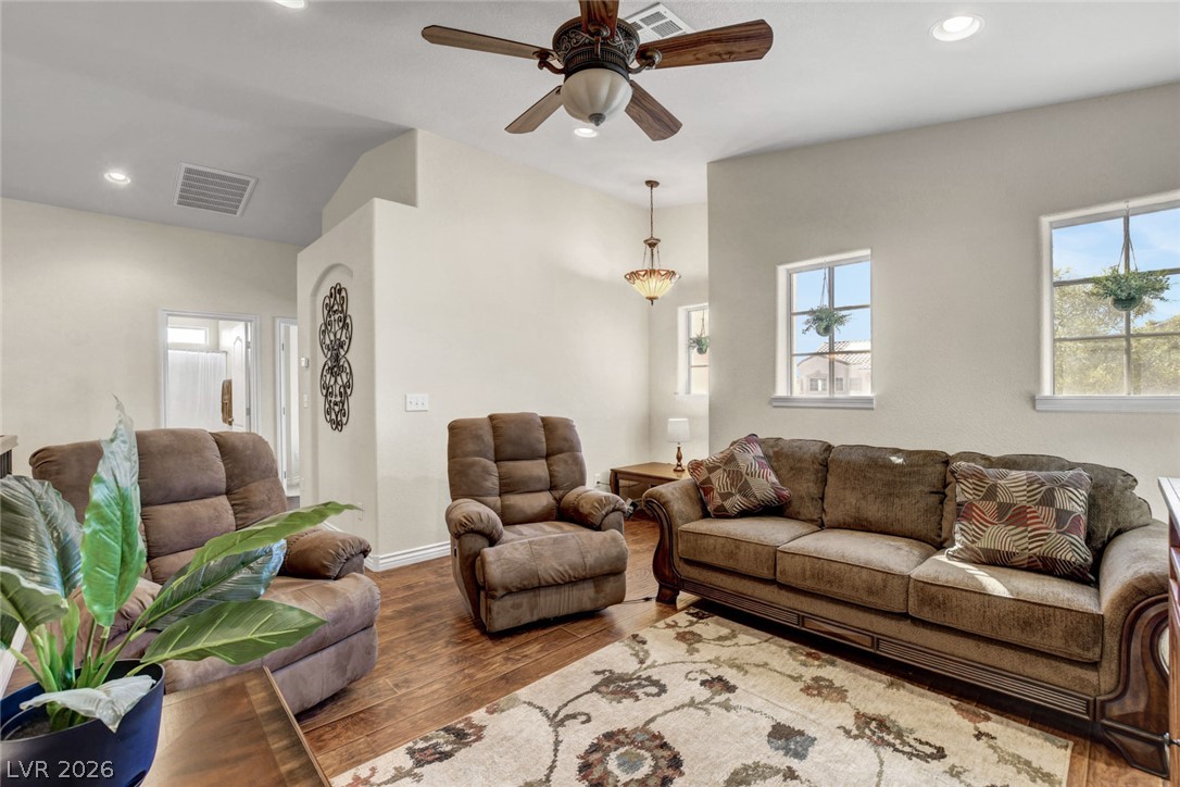 Furnished living room with brown seating, wood-look floors, and a patterned rug.