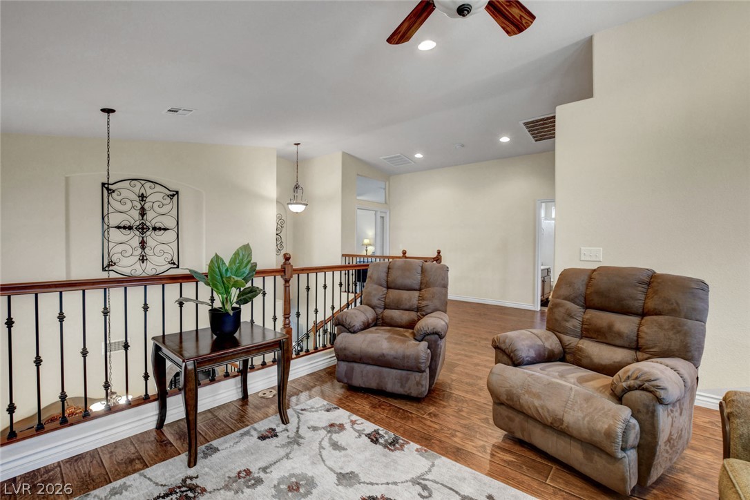 Upstairs sitting area with two recliners, a wood railing, and a patterned rug.