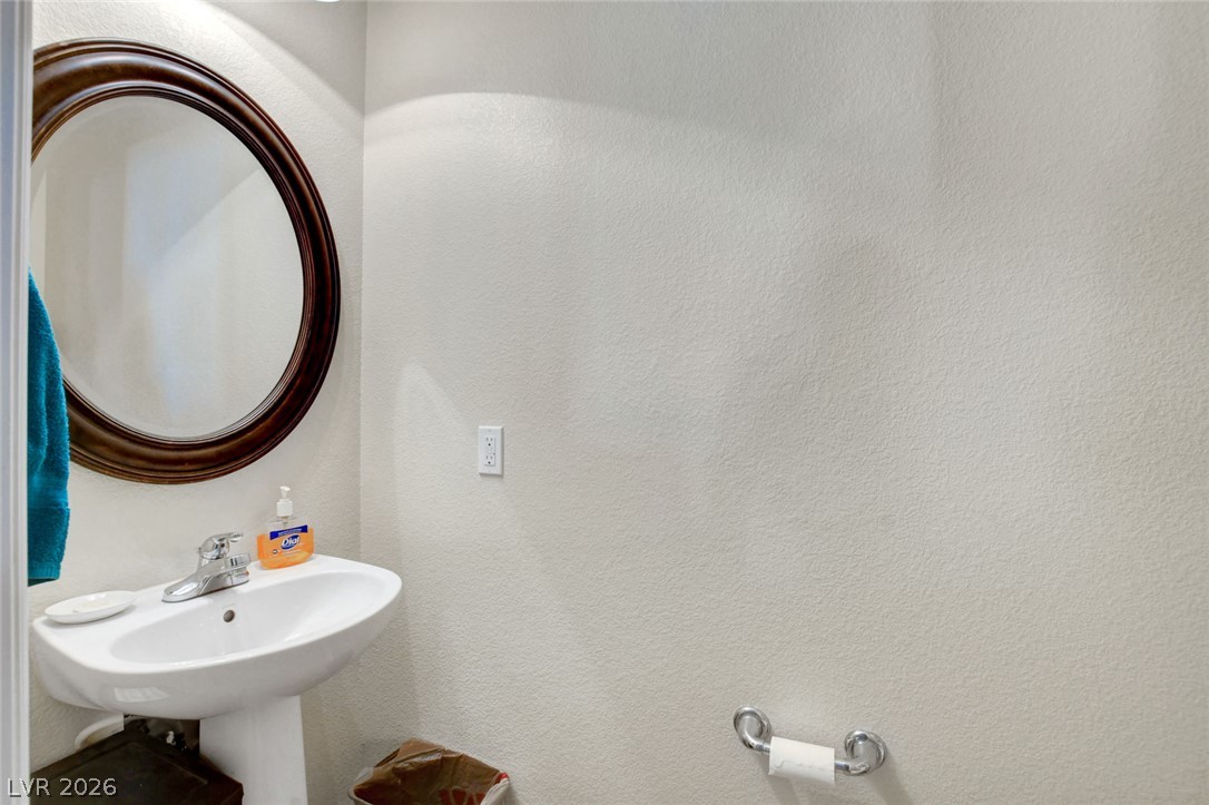 Bathroom pedestal sink beneath an oval dark wood-framed mirror, with a blue towel nearby.