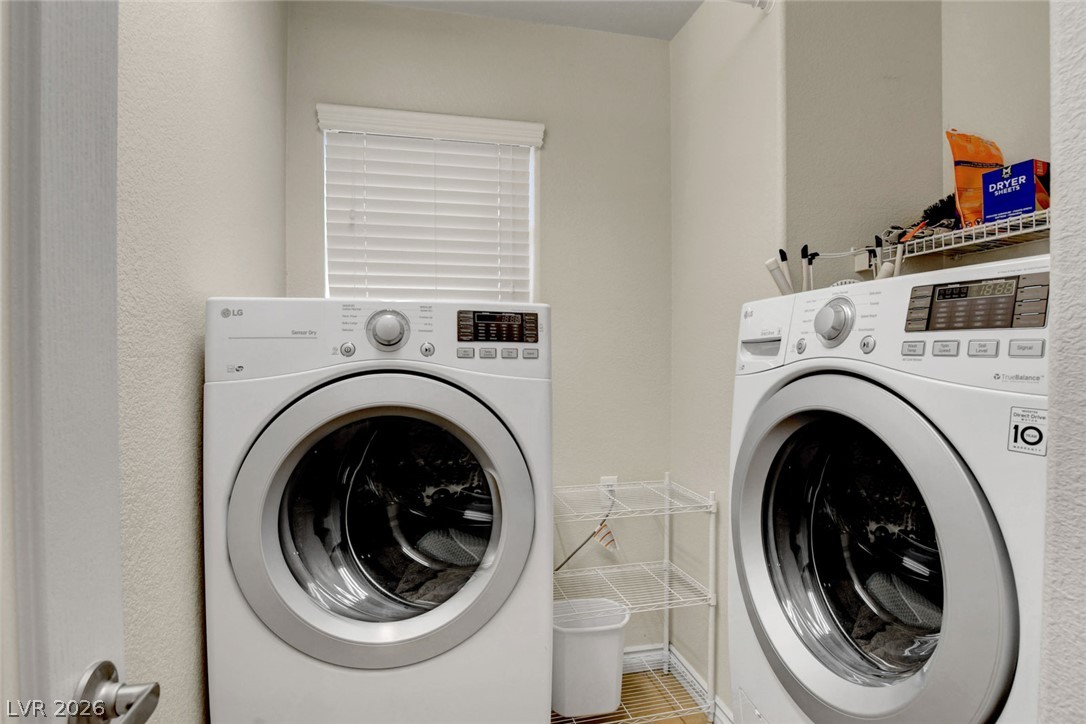Laundry room with front-loading washer and dryer beside white wire shelving.