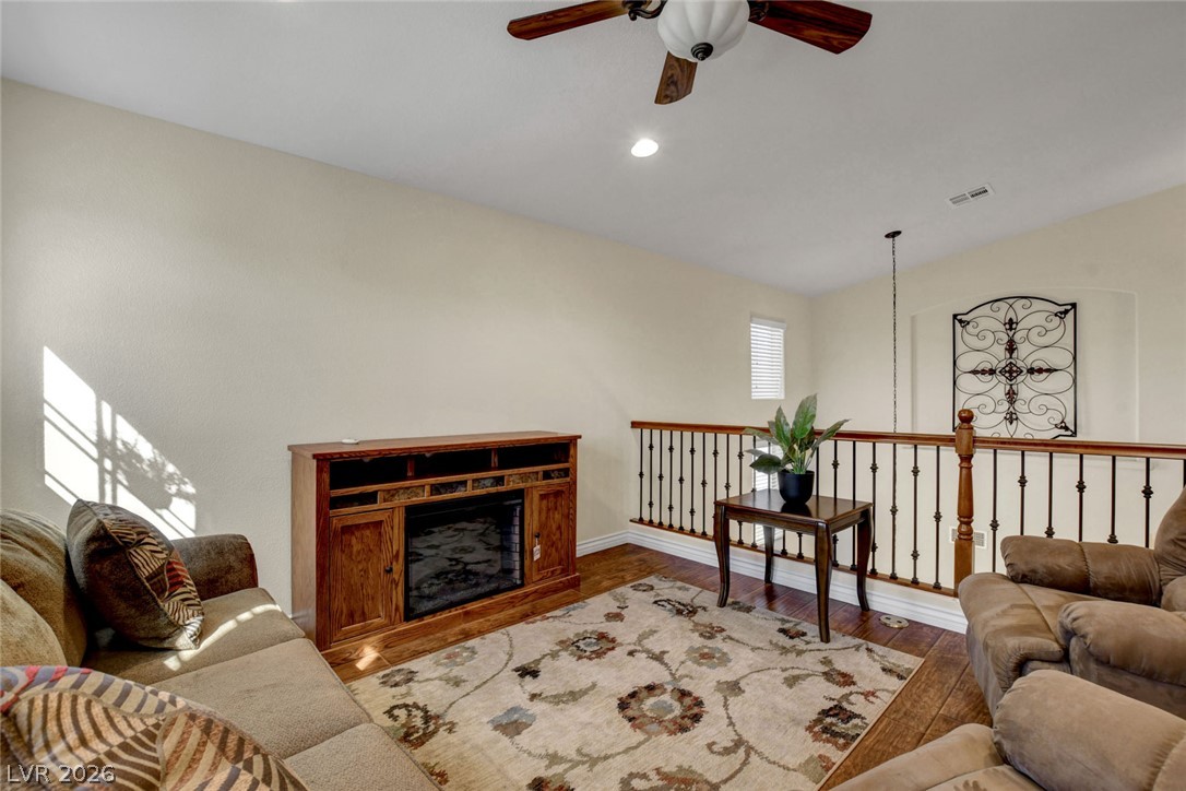Upstairs sitting area with a wooden fireplace console, patterned rug, and black metal railing.
